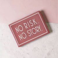 Rechteckiger Keramik-Kühlschrankmagnet (7x5 cm) im Querformat mit altrosafarbener, seidenmatter Glasur. Umrahmt von einer weißen Linie steht der Schriftzug 'NO RISK. NO STORY.' im fühlbaren 3D-Relief.