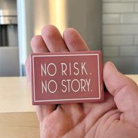 Rechteckiger Keramik-Kühlschrankmagnet (7x5 cm) im Querformat mit altrosafarbener, seidenmatter Glasur. Umrahmt von einer weißen Linie steht der Schriftzug 'NO RISK. NO STORY.' im fühlbaren 3D-Relief.