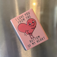 Rechteckiger Keramik-Kühlschrankmagnet (7x5 cm) mit seidenmatter Glasur in Altrosa. Abgebildet ist der schwarze Schriftzug 'I LOVE YOU FROM THE BUTTOM OF MY HEART' mit einem lustigen Herz inklusive Po im fühlbaren 3D-Relief.