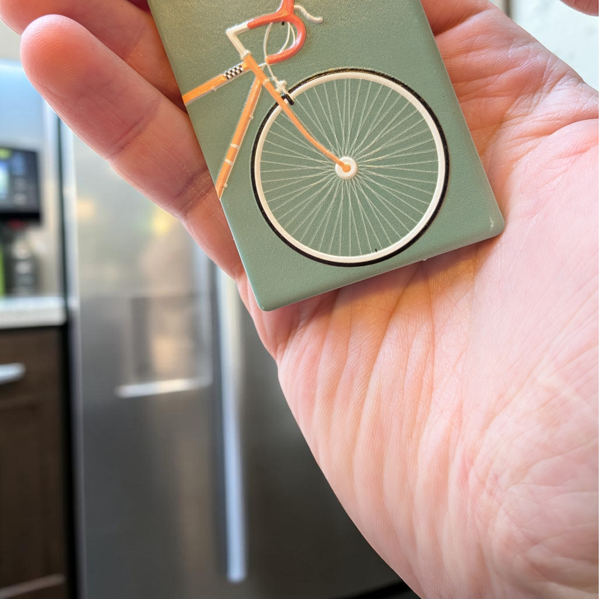 Rechteckiger Keramikmagnet mit einer detaillierten Illustration eines Rennfahrers auf einem Rennrad. Seidenmatte weiße Oberfläche mit haptischem Relief der Rad-Konturen im Vintage-Stil.