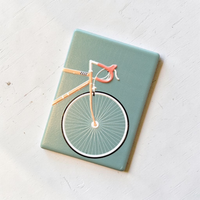 Rechteckiger Keramikmagnet mit einer detaillierten Illustration eines Rennfahrers auf einem Rennrad. Seidenmatte weiße Oberfläche mit haptischem Relief der Rad-Konturen im Vintage-Stil.