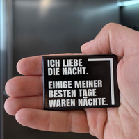 Rechteckiger Keramik-Kühlschrankmagnet (7x5 cm) im Querformat mit schwarzer, seidenmatter Glasur. Auf schwarzem Grund steht der weiße Schriftzug 'ICH LIEBE DIE NACHT. EINIGE MEINER BESTEN TAGE WAREN NÄCHSTE.' im fühlbaren 3D-Relief.