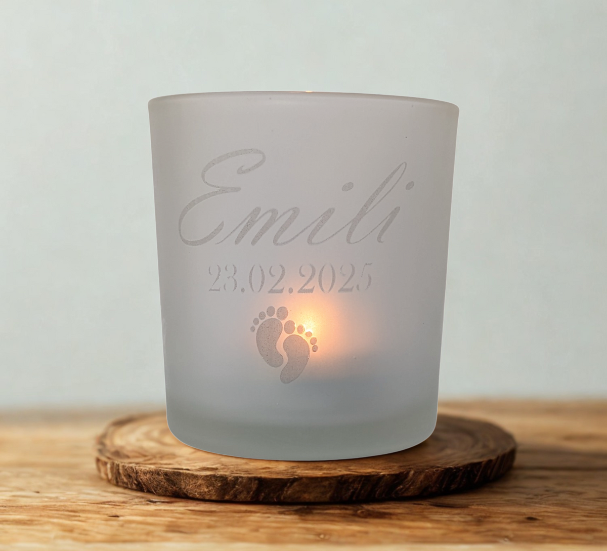 Frostweißes Teelichtglas mit individueller Gravur von Name und Geburtsdatum, darunter zwei Babyfüße – liebevolles Geschenk zur Geburt oder Erinnerung an Sternenkinder.