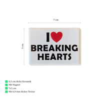 Rechteckiger Keramik-Kühlschrankmagnet (7x5 cm) im Querformat mit seidenmatter Glasur. Auf weißem Grund steht der schwarze Schriftzug 'I BREAKING HEARTS' mit einem leuchtend roten Herz-Symbol im fühlbaren 3D-Relief.