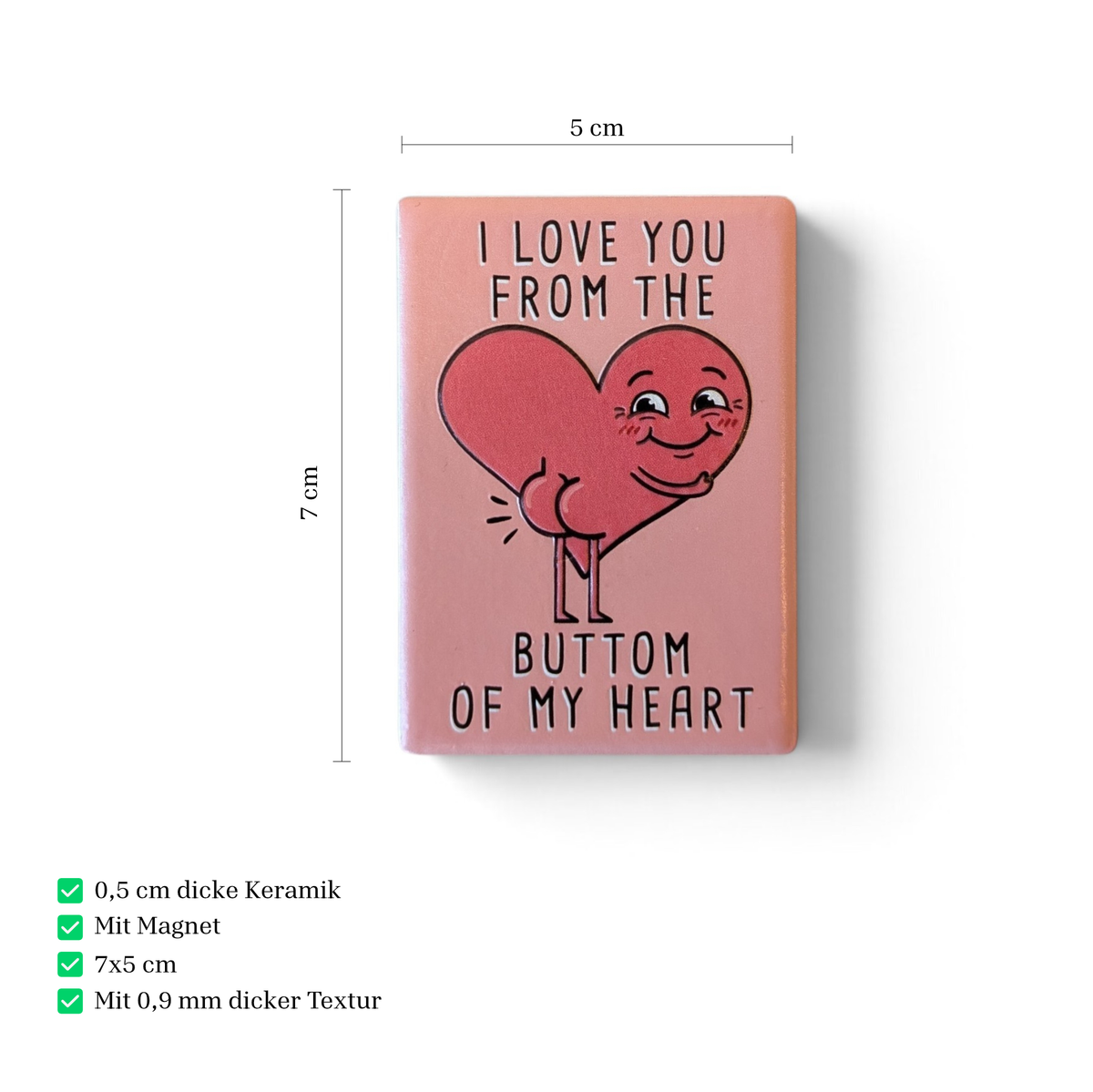 Rechteckiger Keramik-Kühlschrankmagnet (7x5 cm) mit seidenmatter Glasur in Altrosa. Abgebildet ist der schwarze Schriftzug 'I LOVE YOU FROM THE BUTTOM OF MY HEART' mit einem lustigen Herz inklusive Po im fühlbaren 3D-Relief.