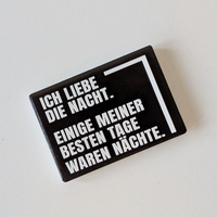 Rechteckiger Keramik-Kühlschrankmagnet (7x5 cm) im Querformat mit schwarzer, seidenmatter Glasur. Auf schwarzem Grund steht der weiße Schriftzug 'ICH LIEBE DIE NACHT. EINIGE MEINER BESTEN TAGE WAREN NÄCHSTE.' im fühlbaren 3D-Relief.